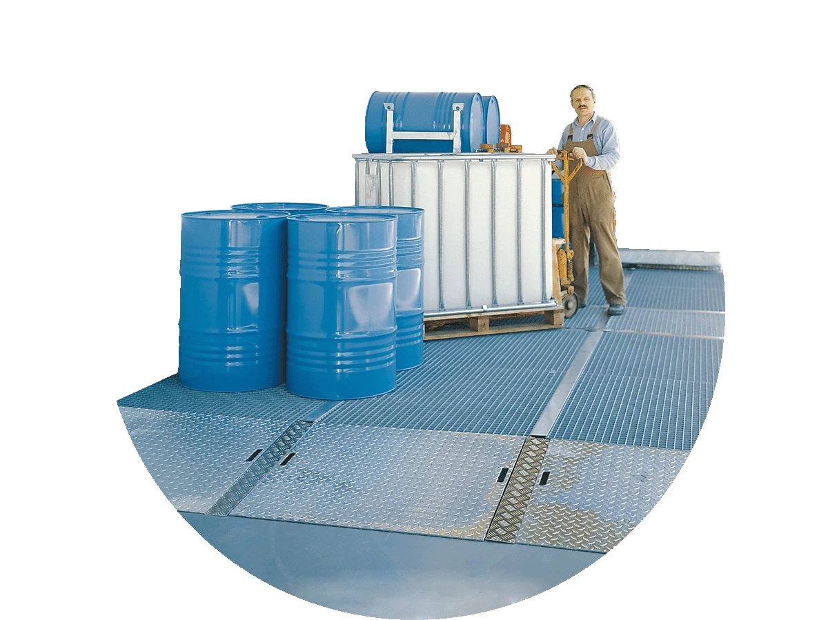 Bodenschutzwannen als Flaechenschutzsystem Ein Arbeiter faehrt mit einem Hubwagen einen IBC auf flache Auffangwannen.